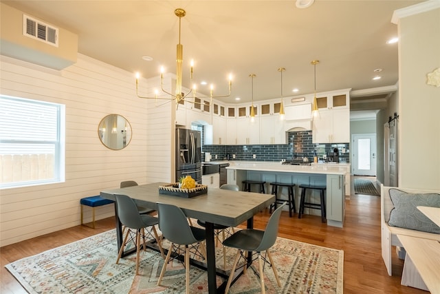 dining room with wooden walls, a barn door, dark hardwood / wood-style floors, and crown molding