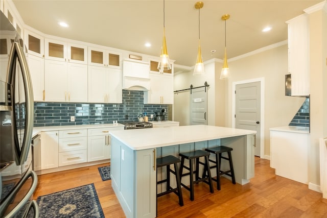 kitchen with white cabinetry, a center island, a barn door, light hardwood / wood-style floors, and appliances with stainless steel finishes