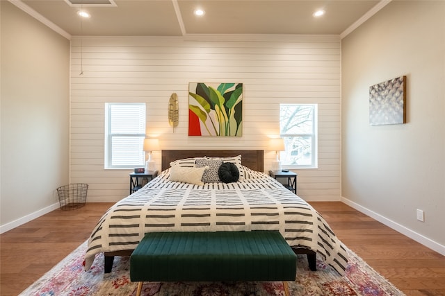 bedroom featuring wood walls, ornamental molding, and hardwood / wood-style flooring