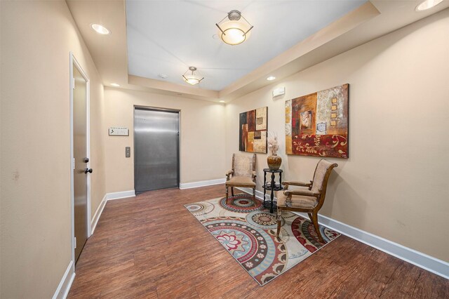 living area featuring a raised ceiling, dark hardwood / wood-style flooring, and elevator