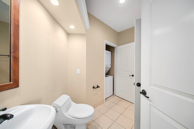 bathroom featuring sink, tile flooring, stacked washing maching and dryer, and toilet