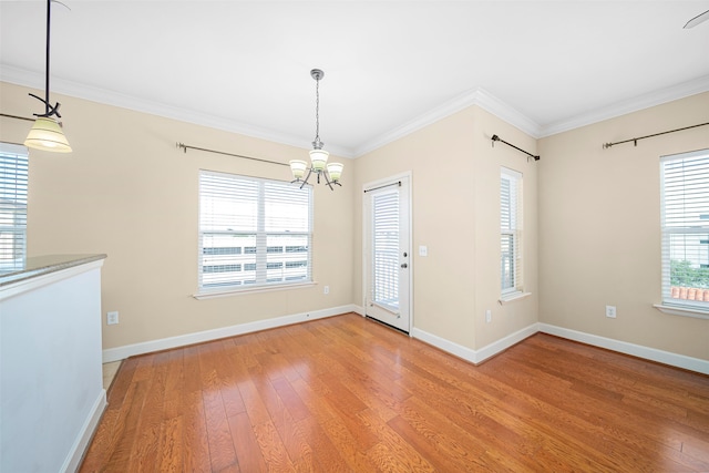 empty room with crown molding, an inviting chandelier, and hardwood / wood-style floors