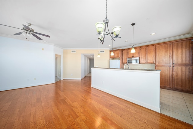 kitchen featuring tasteful backsplash, white refrigerator, pendant lighting, light tile floors, and ornamental molding