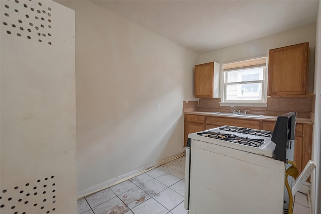 kitchen featuring decorative backsplash, light tile patterned flooring, sink, and gas range gas stove