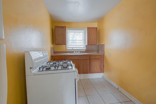 kitchen featuring tasteful backsplash, sink, light tile patterned floors, and white range with gas stovetop