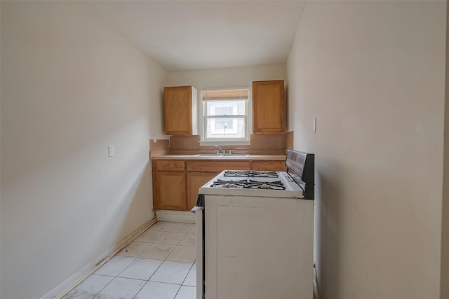 kitchen featuring backsplash, sink, light tile patterned floors, and white stove