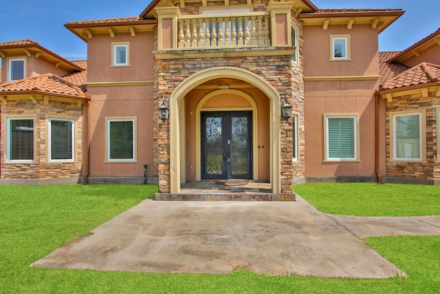 17018 Grant Rd, Cypress, TX 77429 - view of exterior entry with a balcony, stucco siding, a lawn, and stone siding