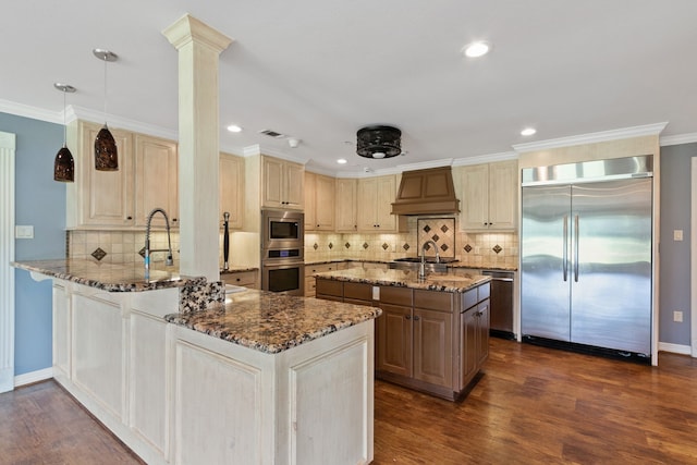 kitchen with built in appliances, backsplash, custom exhaust hood, dark stone counters, and dark hardwood / wood-style floors