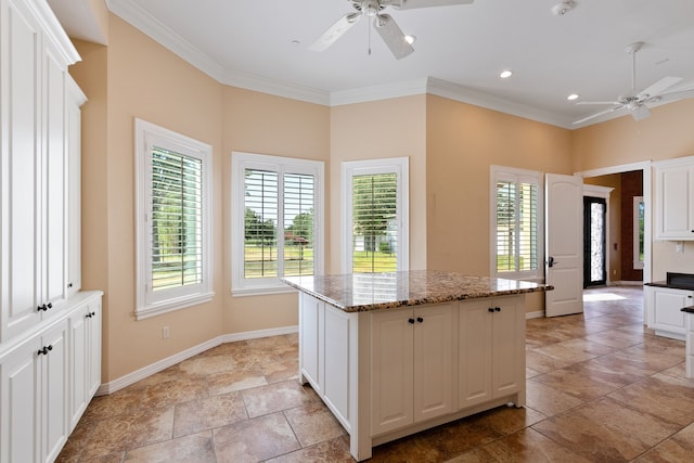 kitchen featuring light stone counters, ceiling fan, white cabinetry, light tile patterned floors, and a kitchen island