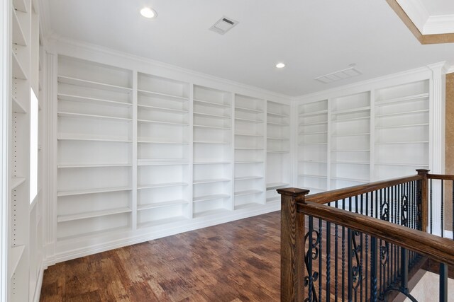 hall with dark wood-type flooring, built in shelves, and crown molding