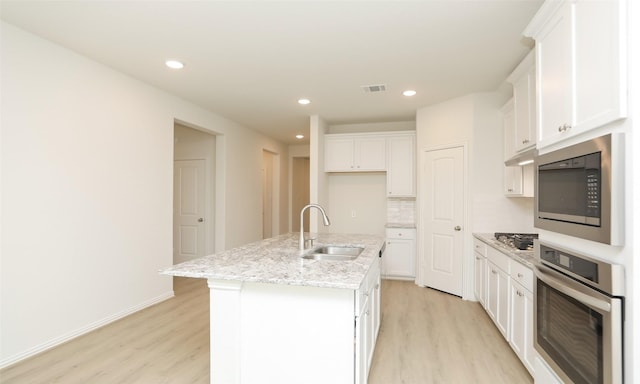 kitchen with a center island with sink, white cabinets, sink, and appliances with stainless steel finishes