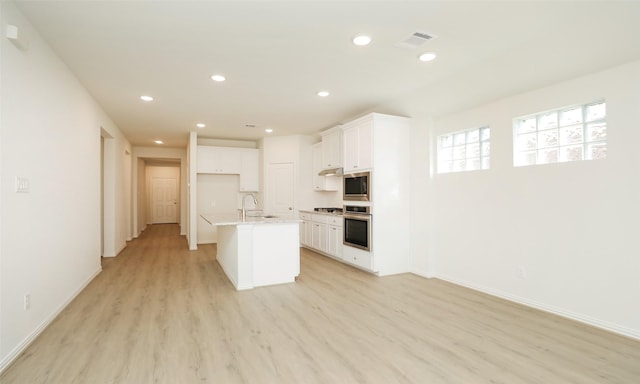 kitchen with sink, stainless steel appliances, an island with sink, light hardwood / wood-style floors, and white cabinets