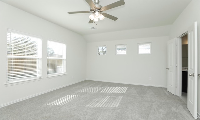 empty room with light colored carpet, a wealth of natural light, lofted ceiling, and ceiling fan