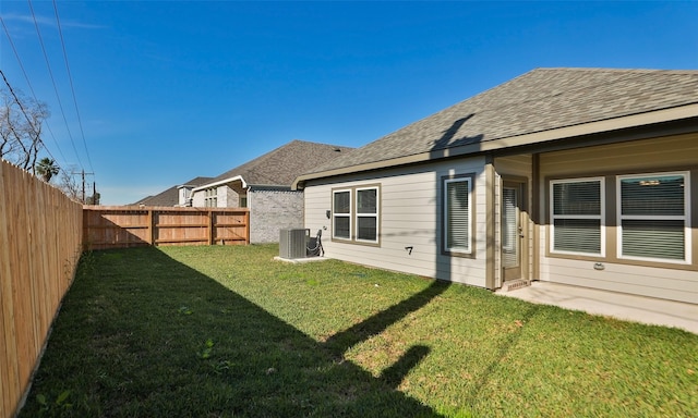 rear view of property with central AC unit and a lawn