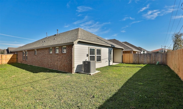 rear view of property featuring a lawn and central air condition unit