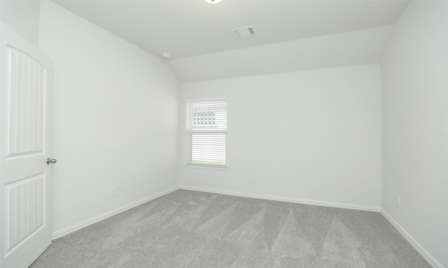 unfurnished room featuring lofted ceiling and light carpet