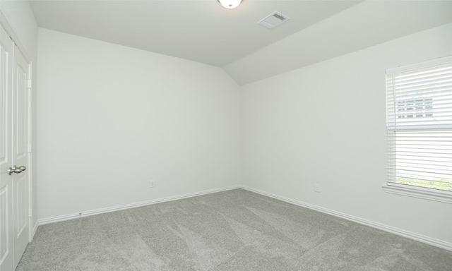 unfurnished room with light colored carpet and lofted ceiling