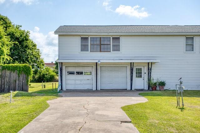 traditional-style house featuring an attached garage, fence, a front lawn, and concrete driveway