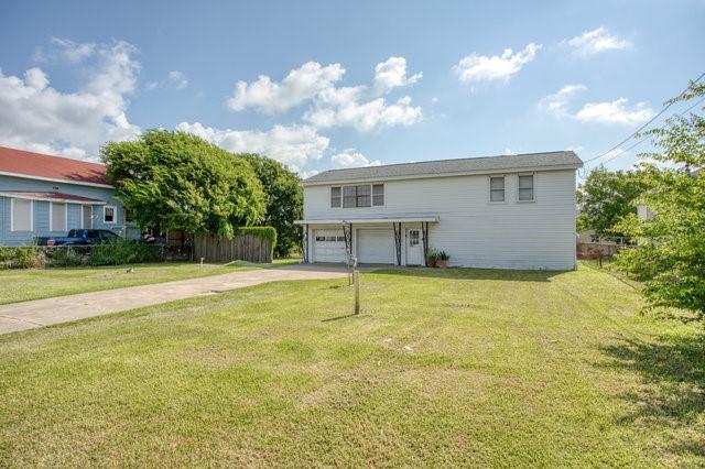 view of front of house with a garage, driveway, a front lawn, and fence