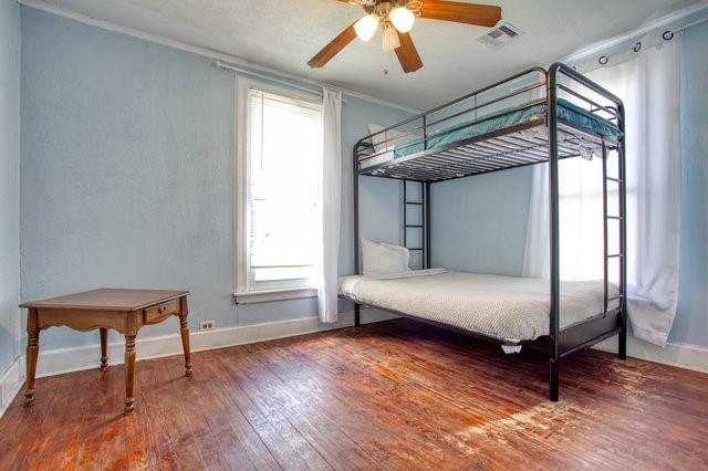 unfurnished bedroom featuring ceiling fan, wood-type flooring, visible vents, and baseboards