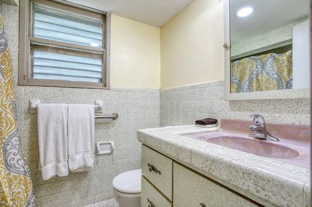 full bathroom featuring tile walls, a wainscoted wall, vanity, and toilet