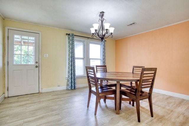 dining area featuring baseboards, visible vents, a chandelier, and crown molding