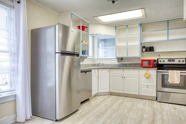 kitchen featuring appliances with stainless steel finishes, white cabinets, light wood finished floors, and open shelves