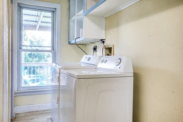 clothes washing area with light wood-type flooring, laundry area, plenty of natural light, and washer and clothes dryer