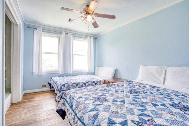 bedroom with ceiling fan, ornamental molding, wood finished floors, and baseboards