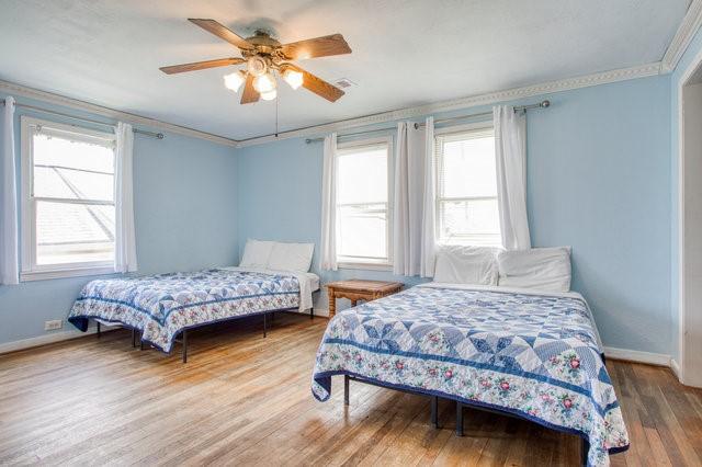 bedroom featuring a ceiling fan, baseboards, ornamental molding, and wood finished floors