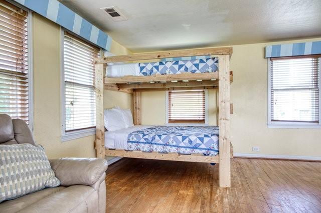 bedroom with hardwood / wood-style flooring, visible vents, and baseboards