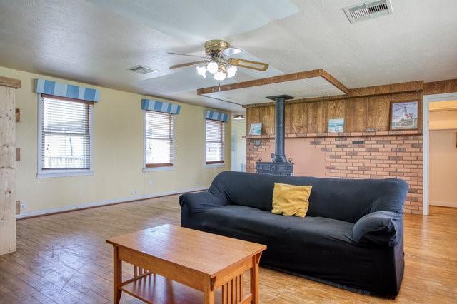 living area featuring a wood stove, light wood-style flooring, and visible vents