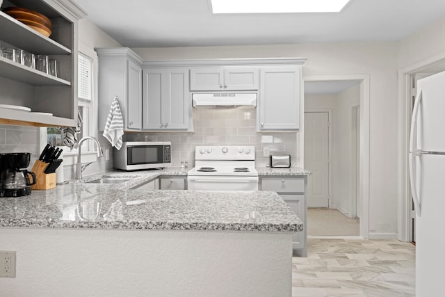 kitchen featuring white appliances, kitchen peninsula, light stone counters, sink, and tasteful backsplash