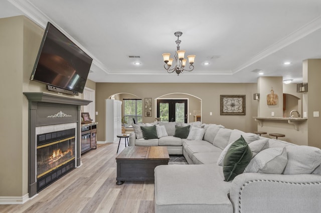 living room featuring a chandelier, french doors, ornamental molding, and light hardwood / wood-style flooring