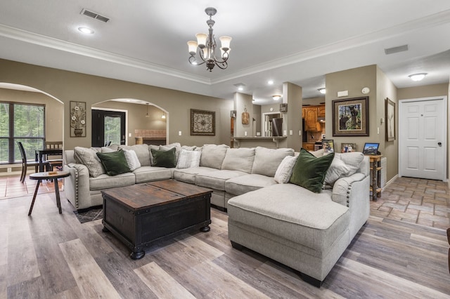 living room with an inviting chandelier, hardwood / wood-style floors, and ornamental molding