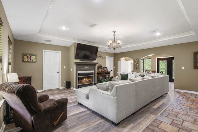 living room with a chandelier, a raised ceiling, and hardwood / wood-style floors