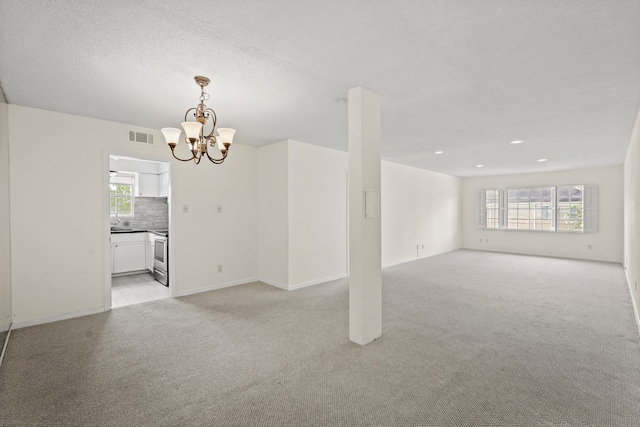 carpeted empty room featuring a notable chandelier