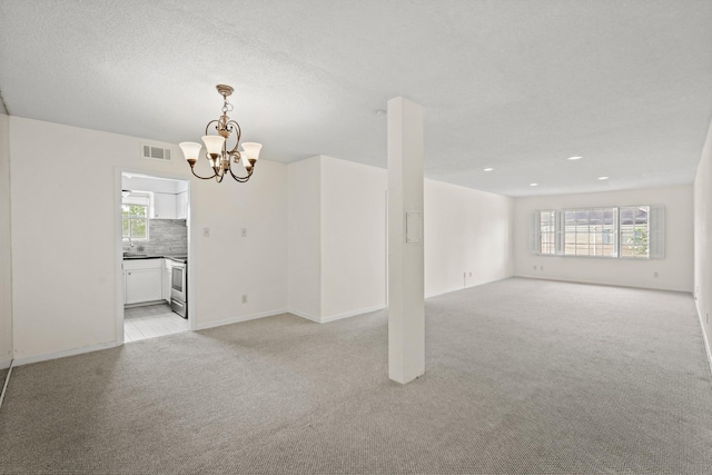 carpeted spare room featuring an inviting chandelier and sink