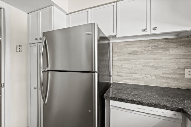 kitchen featuring stainless steel fridge, white cabinetry, white dishwasher, and dark stone counters