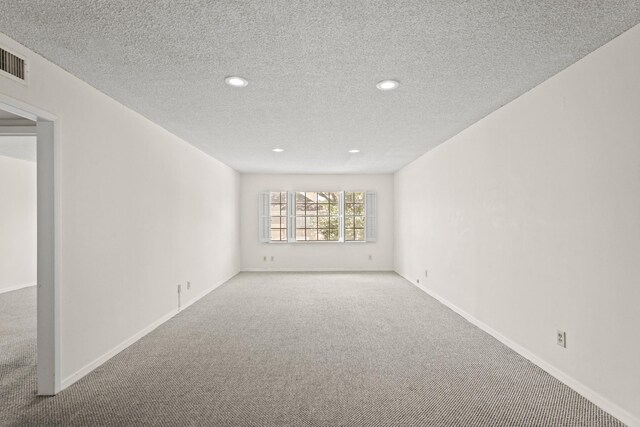 spare room with a textured ceiling and carpet flooring