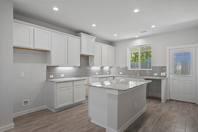 kitchen featuring white cabinets, a center island, and hardwood / wood-style flooring