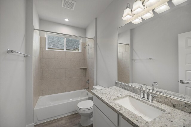 full bathroom featuring vanity, tiled shower / bath combo, and toilet