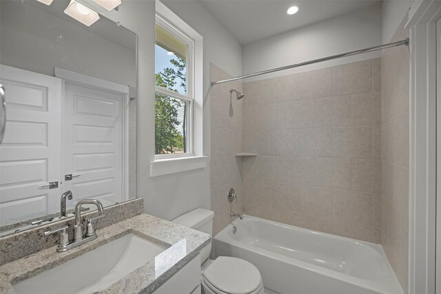 full bathroom with vanity, tiled shower / bath combo, and toilet