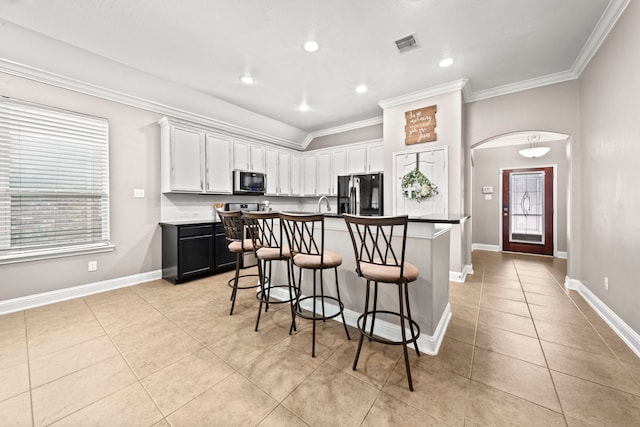 kitchen featuring black fridge with ice dispenser, a kitchen bar, a kitchen island with sink, white cabinetry, and light tile patterned flooring