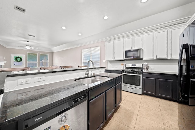 kitchen with appliances with stainless steel finishes, ceiling fan, dark stone counters, white cabinets, and sink