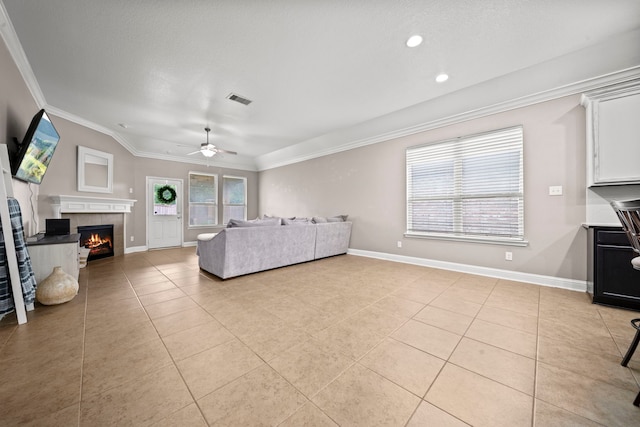 living room featuring a tile fireplace, a textured ceiling, light tile patterned flooring, ceiling fan, and crown molding