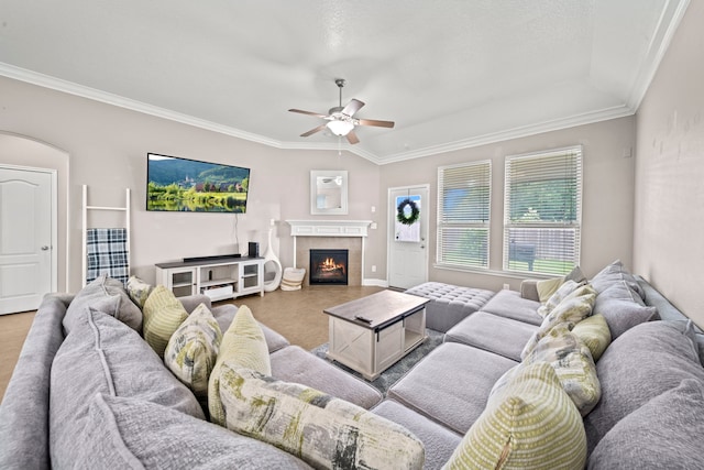 living room featuring a tiled fireplace, ceiling fan, vaulted ceiling, and crown molding