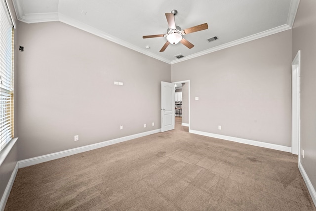 carpeted spare room with ceiling fan, crown molding, and a wealth of natural light