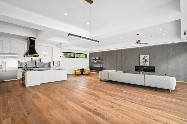 unfurnished living room featuring light hardwood / wood-style flooring and ceiling fan with notable chandelier