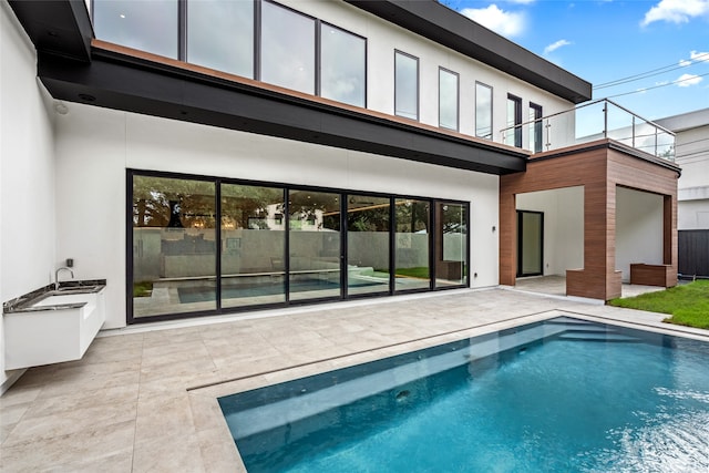 rear view of house with a balcony, a fenced in pool, and a patio area